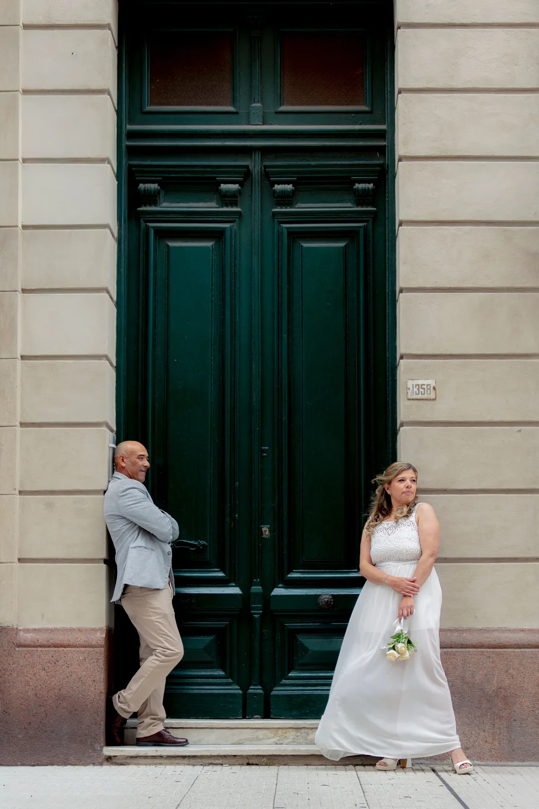 Novios esperando separados frente a una puerta verde antigua